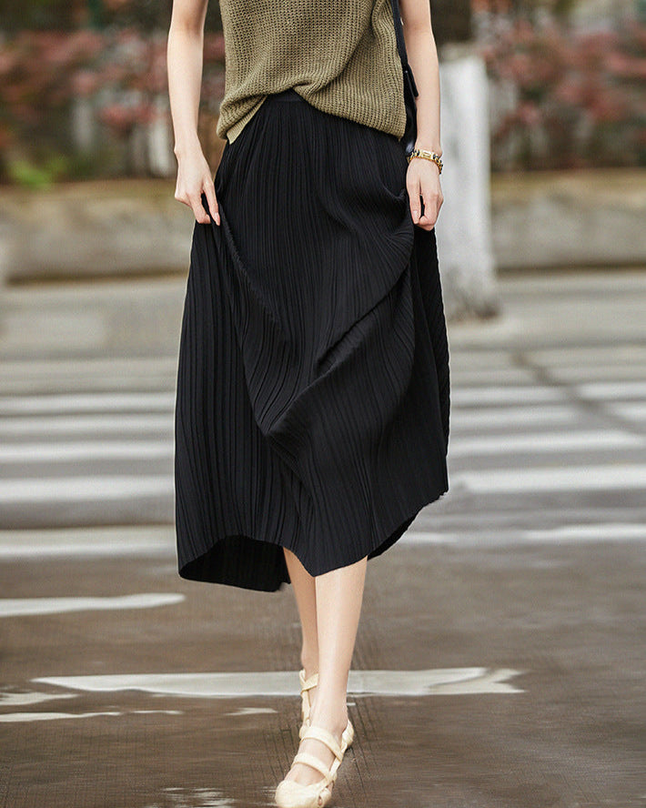 Frau in schwarzem, plissiertem Midirock und beigem Oberteil überquert Straße. Modetrend, Damenmode, eleganter Look, Straßenstil.