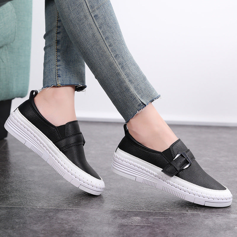 Damen-Sneaker aus schwarzem Leder mit weißer Sohle und Schnalle, getragen zu blauen Jeans. Bequeme Freizeitschuhe für den Alltag.