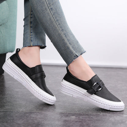 Damen-Sneaker aus schwarzem Leder mit weißer Sohle und Schnalle, getragen zu blauen Jeans. Bequeme Freizeitschuhe für den Alltag.