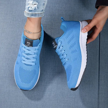Blaue Sportschuhe mit weißer Sohle auf Jeansstoff, getragen von Person mit Jeans. Moderne, atmungsaktive Sneaker für Damen.
