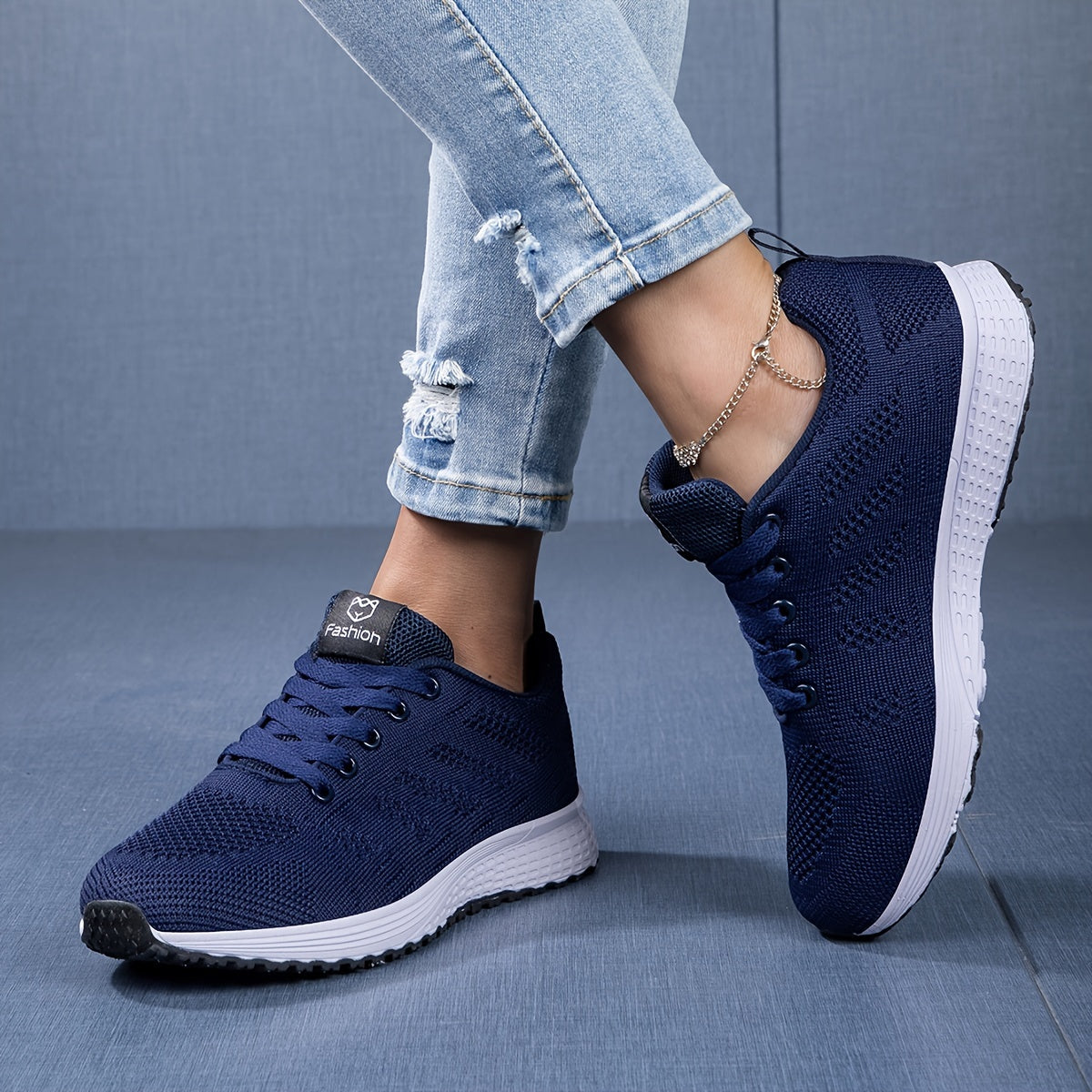 Damen Sneaker in Dunkelblau, atmungsaktiv, mit weißer Sohle. Getragen mit zerrissenen Jeans. Modische Freizeitschuhe für Alltag und Sport.