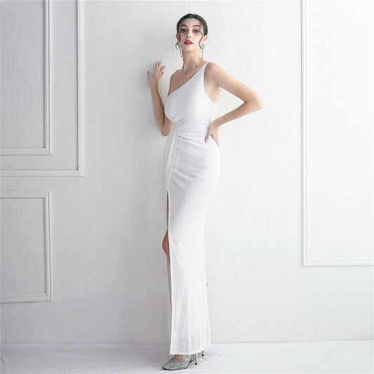 Frau in elegantem, weißem, schulterfreiem Abendkleid mit hohem Schlitz, posiert vor weißer Wand. Perfekt für Mode, Abendmode, Eleganz.