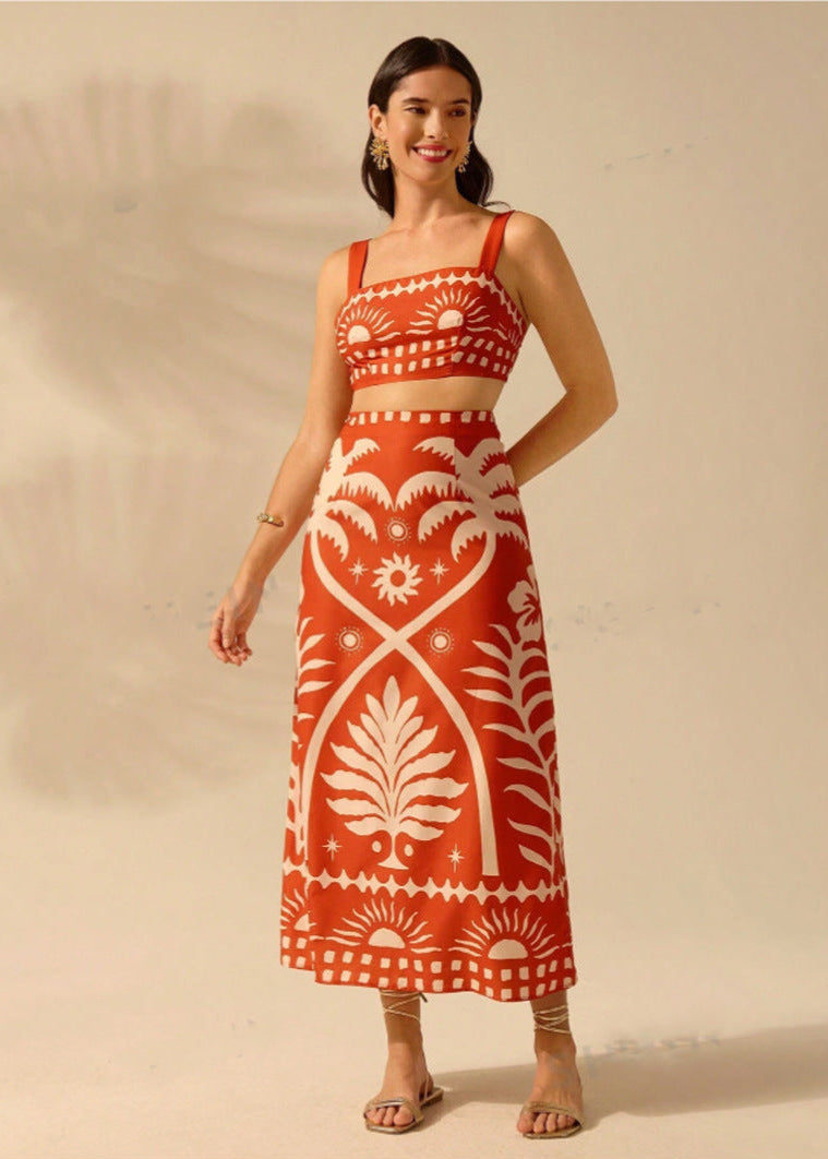 Frau in rotem, ärmellosem Kleid mit weißem, botanischem Muster, lächelt und trägt Sandalen. Elegante Sommermode, stilvolles Design.