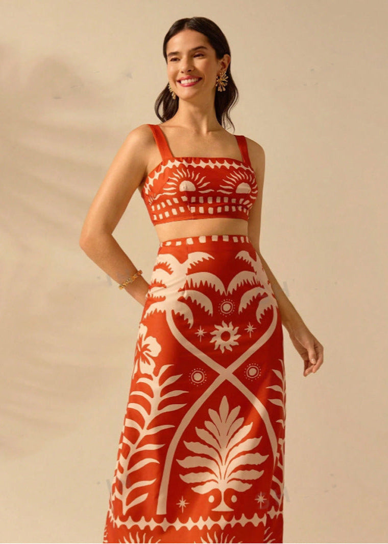 Frau in rotem, gemustertem Kleid mit weißem Blumenmuster, lächelnd, vor neutralem Hintergrund. Elegantes Sommeroutfit, modisches Design.