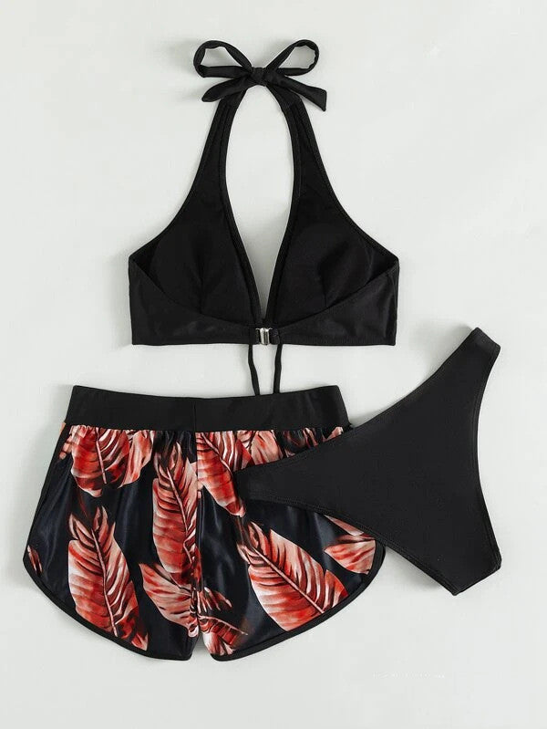 Schwarzer Bikini mit rotem Blattmuster, bestehend aus Neckholder-Oberteil, Shorts und Slip. Perfekt für Strandmode und Sommerurlaub.