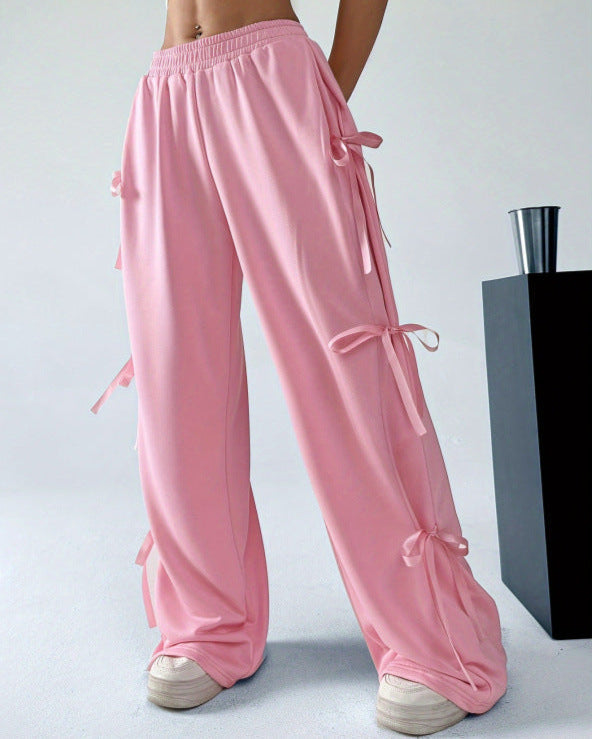 Rosa Damenhose mit Schleifen, weites Bein, modisch, lässig, elastischer Bund, kombiniert mit weißen Sneakern, trendige Damenmode.