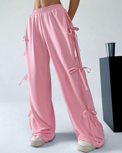Rosa Damenhose mit Schleifen, weites Bein, modisch, lässig, elastischer Bund, kombiniert mit weißen Sneakern, trendige Damenmode.