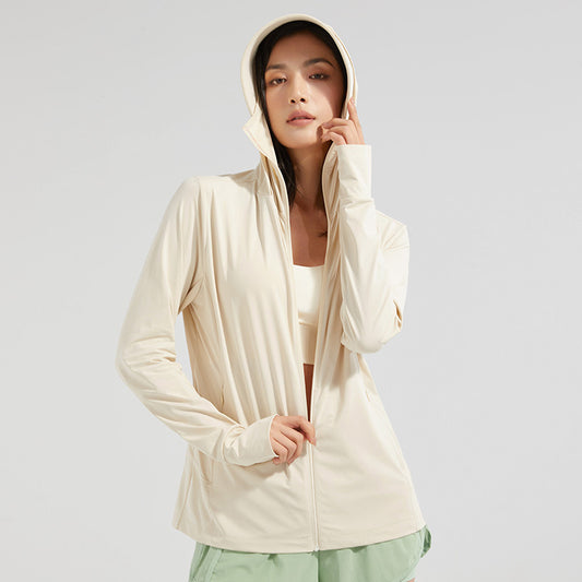 Frau in beiger Sportjacke mit Kapuze, trägt grünen Rock. Modische Sportbekleidung, ideal für Fitness und Freizeit. Minimalistischer Stil.
