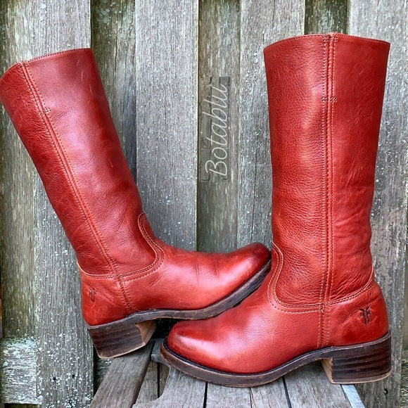 Rote Lederstiefel mit Blockabsatz vor Holzhintergrund. Vintage Damenstiefel, kniehoch, robustes Design. Perfekt für Herbstmode und Outdoor-Aktivitäten.