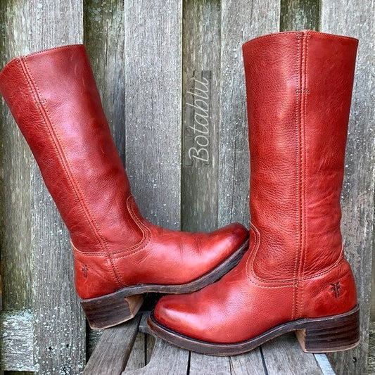 Rote Lederstiefel mit Blockabsatz vor Holzhintergrund. Vintage Damenstiefel, kniehoch, robustes Design. Perfekt für Herbstmode und Outdoor-Aktivitäten.