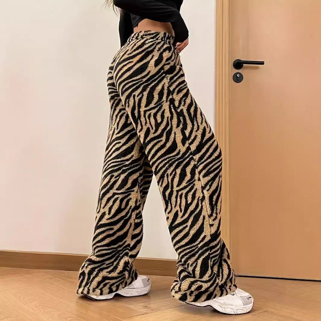 Frau in modischer, weit geschnittener Hose mit Zebramuster, kombiniert mit weißen Sneakers. Trendige Damenmode, Animal-Print, Streetwear-Look.