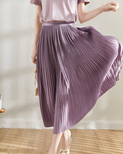 Frau in fliederfarbenem, plissiertem Midirock, schwingend, modisch, elegant, Sommermode, Innenraum, Holzboden, stilvoll, feminin.