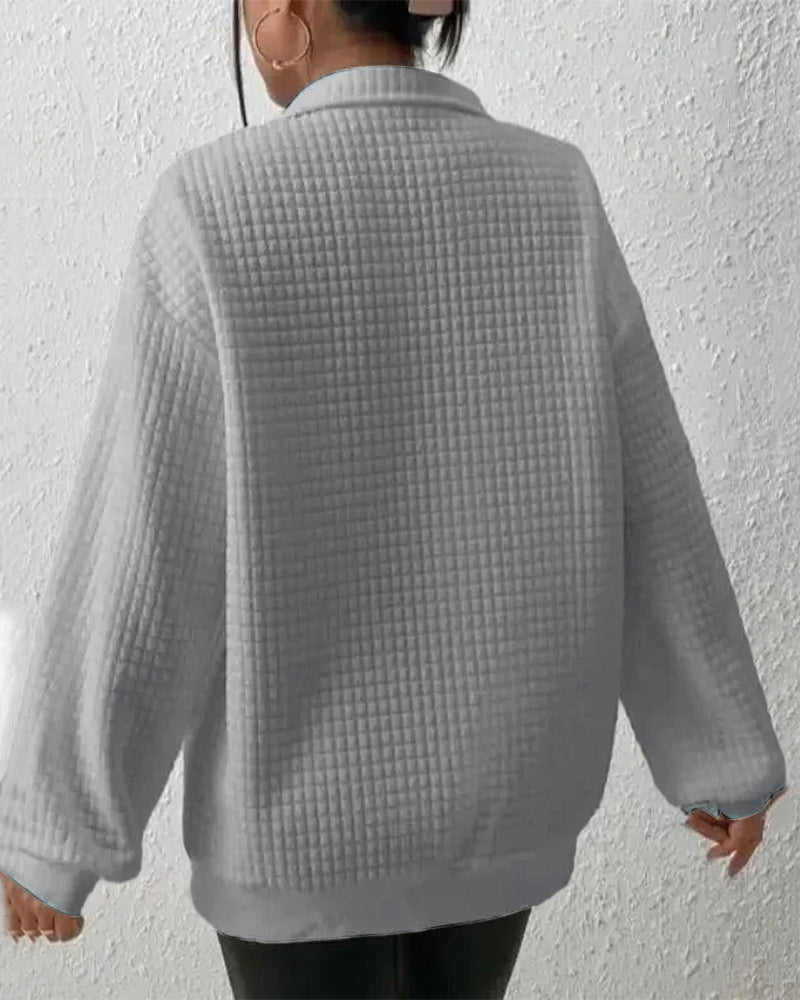 Frau in grauem, strukturiertem Pullover mit Karomuster, Rückansicht. Modetrend, Herbstmode, bequeme Kleidung, stilvoller Look.
