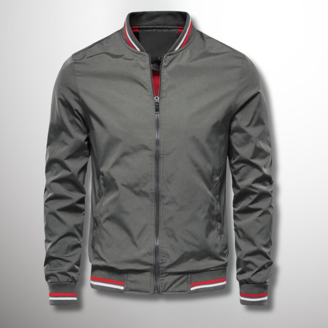 Graue Bomberjacke mit Reißverschluss, roten und weißen Streifen an Kragen und Bündchen, modisch und vielseitig für Herrenmode.