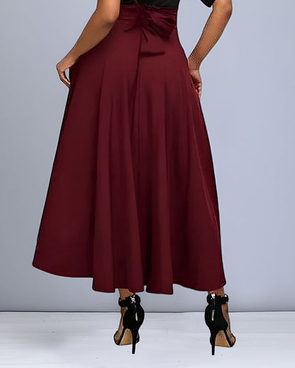 Rückansicht einer Frau in einem eleganten, weinroten Maxirock und schwarzen High Heels. Modische Damenbekleidung, stilvoller Look.