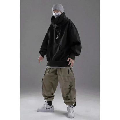 Grauer Hoodie, beiger Cargohose, weiße Sneaker, graue Mütze, Maske; urbaner Streetwear-Look, lässige Mode, trendige Herrenbekleidung.