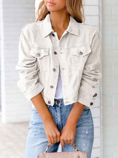 Frau in weißer Jeansjacke und blauer Jeans, hält eine beige Handtasche. Modetrend, lässiger Look, Damenmode, Streetstyle, Frühlingsoutfit.