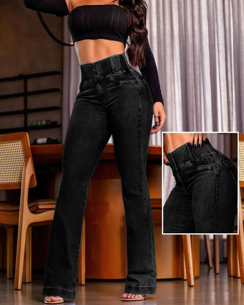 Frau in schwarzer, hoch taillierter Schlaghose und schwarzem Crop-Top vor Holztisch. Modetrend, Damenbekleidung, stilvolle Jeans.
