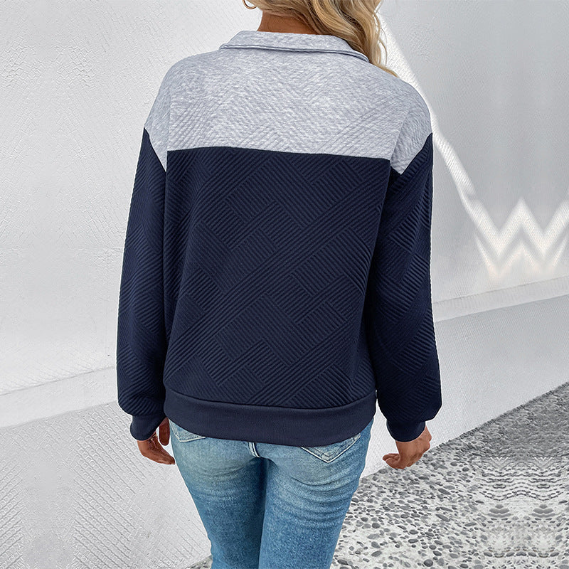Frau in zweifarbigem Pullover, dunkelblau und grau, mit geometrischem Muster, trägt blaue Jeans. Mode, Damenbekleidung, Freizeitlook.