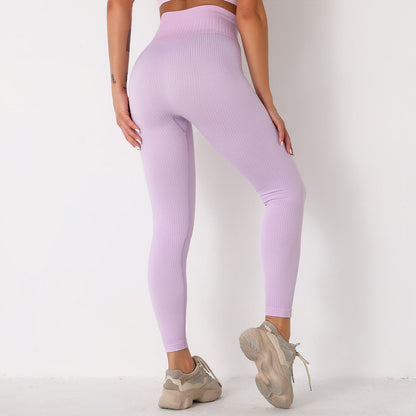Frau in lila nahtloser Leggings, Rückansicht, trägt beige Sneaker. Sportmode, Fitnessbekleidung, bequeme Leggings für Damen.