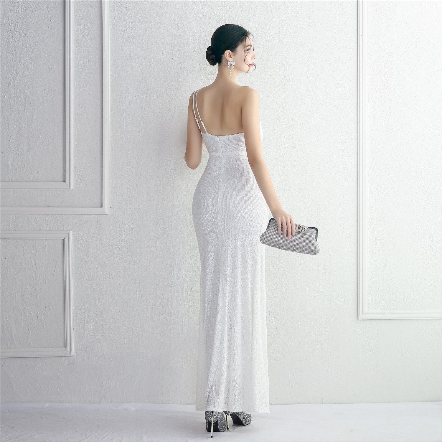 Frau in elegantem, weißem Abendkleid mit Pailletten, hält silberne Clutch. Perfekt für Gala, Hochzeit oder Abendveranstaltung. Eleganz, Mode, Abendgarderobe.