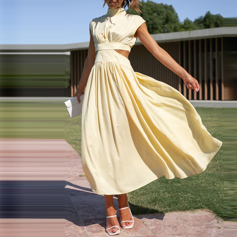 Frau in elegantem, gelbem Sommerkleid mit Cut-Outs, hält weiße Clutch, steht auf Rasen vor modernem Gebäude. Mode, Damenkleider, Sommeroutfit.