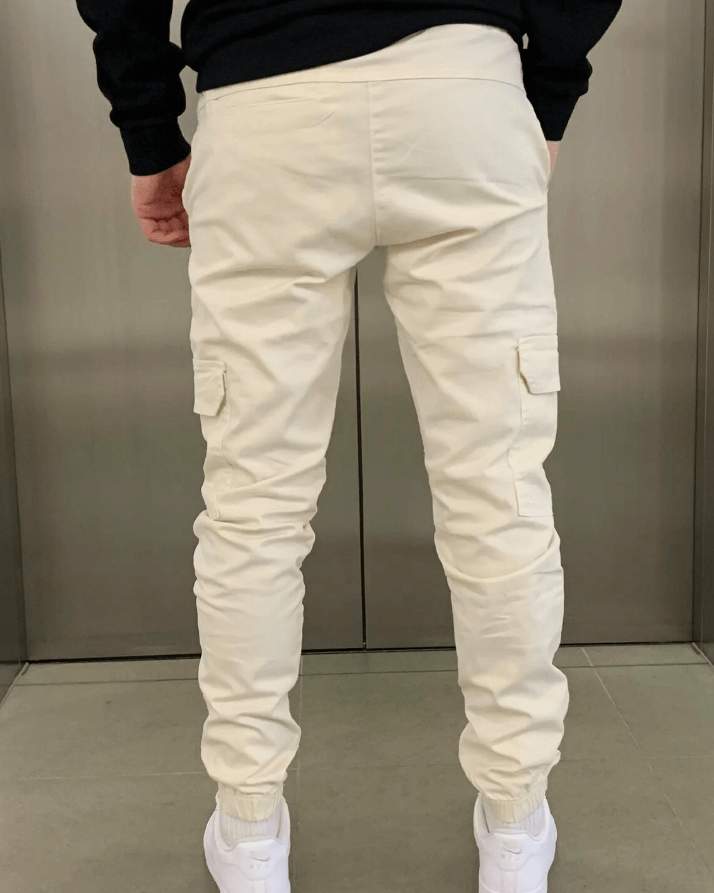 Weiße Cargo-Hose für Herren, Rückansicht. Bequeme Passform, elastische Bündchen, Taschen an den Seiten. Ideal für Freizeitmode und Streetwear.