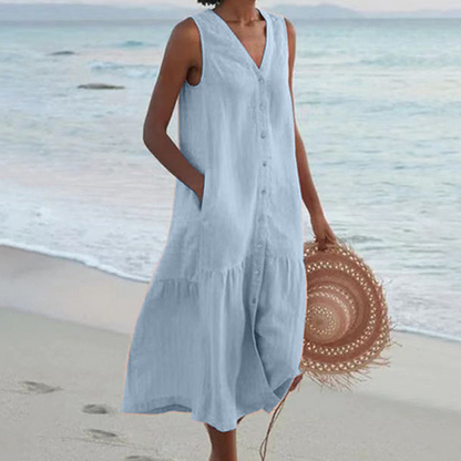 Frau in hellblauem Sommerkleid am Strand, hält runden Strohhut. Strandmode, Sommerkleid, Damenbekleidung, Strandspaziergang.