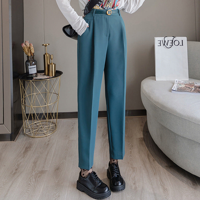 Damenhose in Türkis, elegant geschnitten, kombiniert mit schwarzen Schuhen. Moderne Einrichtung im Hintergrund. Perfekt für stilvolle Outfits.