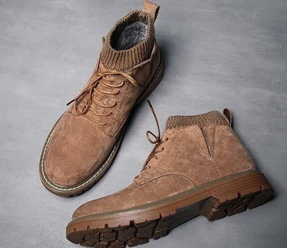 Braune Wildleder-Winterstiefel mit Schnürung und gestricktem Knöchelkragen auf grauem Hintergrund. Herrenmode, warme Schuhe, Outdoor-Boots.