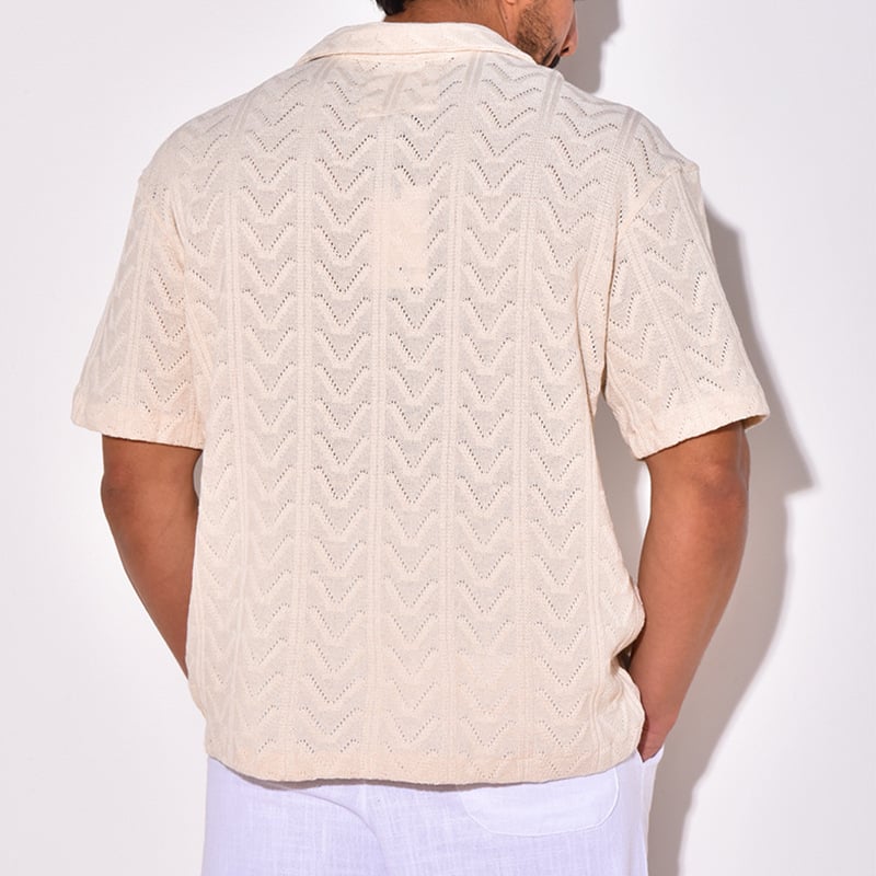 Rückansicht eines Mannes in beigem, gehäkeltem Kurzarmhemd mit Chevron-Muster, kombiniert mit weißer Hose. Sommermode, Herrenbekleidung, lässiger Stil.