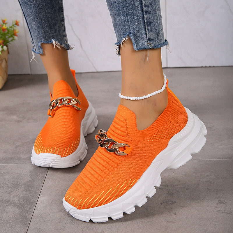 Orange Sneaker mit Kettendetail, getragen von Person in Jeans. Modische Damen-Sportschuhe, trendige Freizeitschuhe, bequeme Laufsohle.