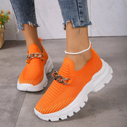 Orange Sneaker mit Kettendetail, getragen von Person in Jeans. Modische Damen-Sportschuhe, trendige Freizeitschuhe, bequeme Laufsohle.