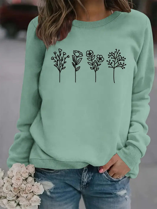 Frau in mintgrünem Pullover mit Blumenmuster, hält Rosenstrauß. Modischer Freizeitlook, ideal für Herbstmode und Streetstyle.