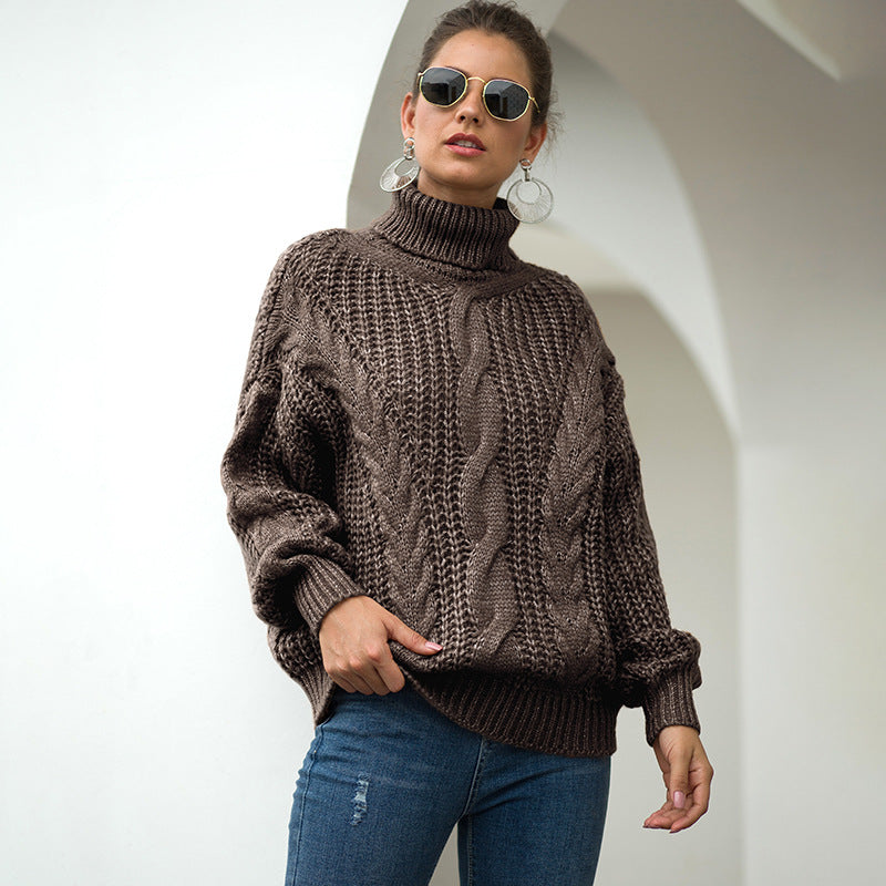 Frau in braunem Strickpullover und blauer Jeans, trägt Sonnenbrille und große Ohrringe, steht vor weißem Hintergrund. Modetrend Herbst/Winter.