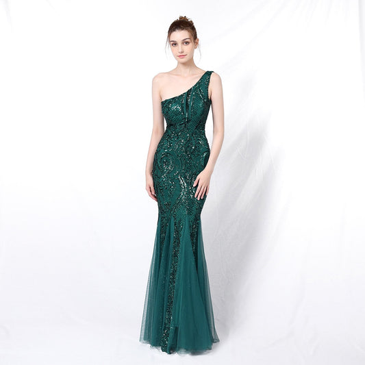 Frau in elegantem, smaragdgrünem, schulterfreiem Abendkleid mit Pailletten, posiert vor weißem Hintergrund. Perfekt für Gala oder Ball.