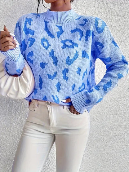 Frau in blauem Leopardenmuster-Pullover, weiße Hose, hält weiße Tasche. Modetrend, stilvoller Look, Herbstmode, Streetstyle.