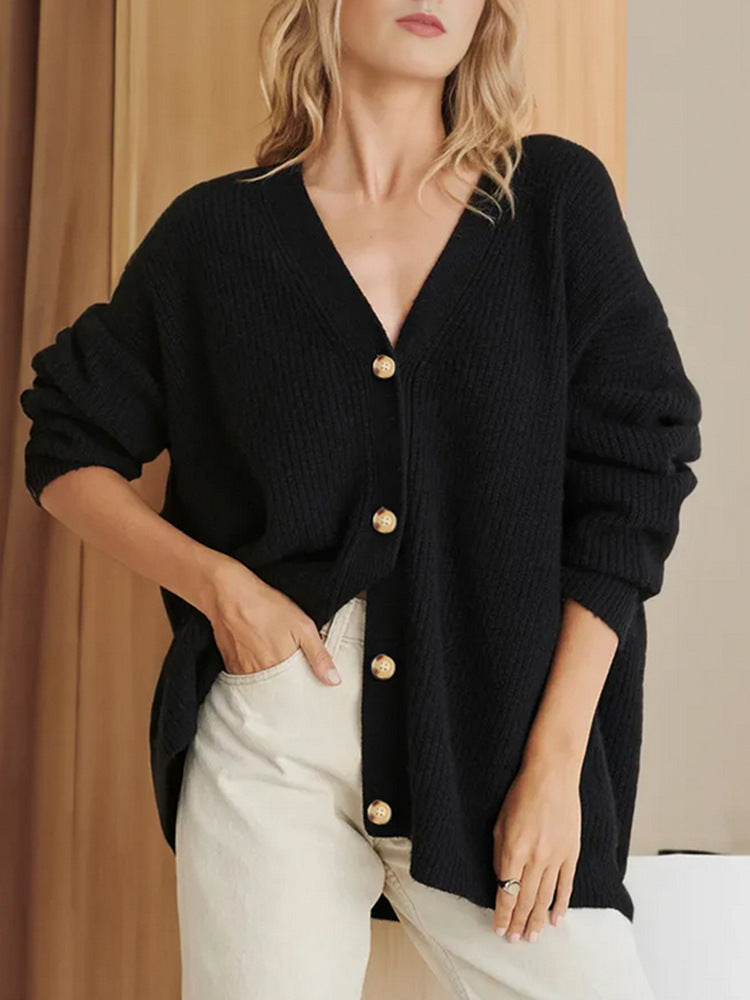 Frau trägt schwarzen Strick-Cardigan mit goldenen Knöpfen, kombiniert mit beigen Hosen. Modetrend, Herbstmode, Damenbekleidung.