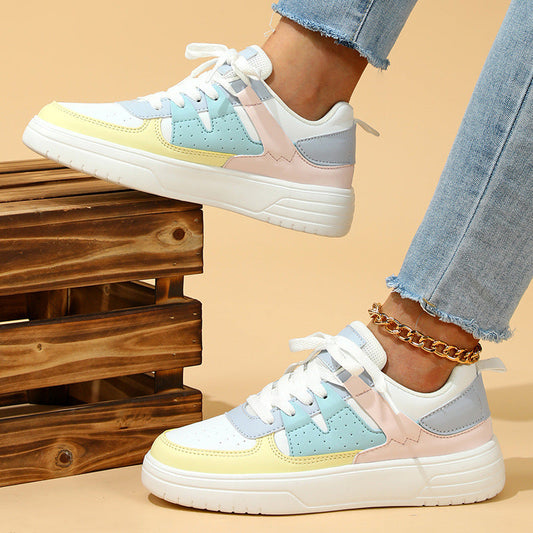 Bunte Damen-Sneaker mit Pastellfarben, weißer Sohle und Schnürsenkeln, getragen mit Jeans. Modische Freizeitschuhe für den Alltag.