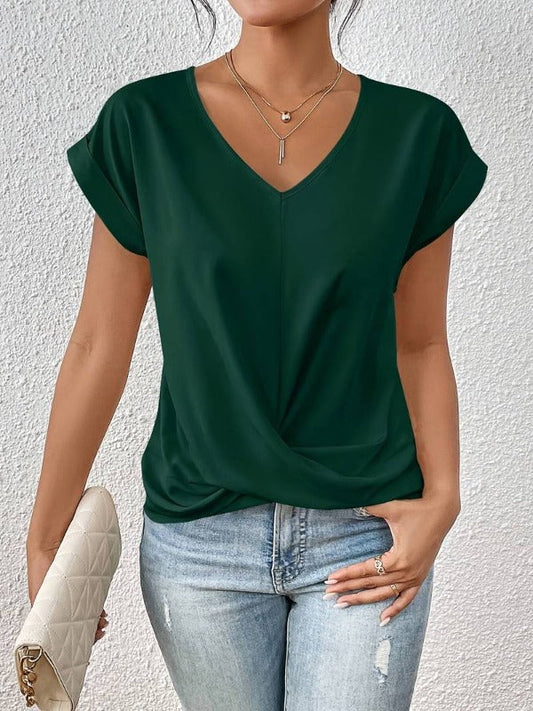 Frau in dunkelgrünem V-Ausschnitt-Shirt, hellblauer Jeans, hält weiße gesteppte Clutch. Modetrend, lässiger Stil, Damenmode.