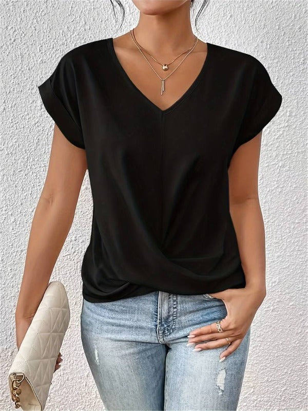 Frau in schwarzem V-Ausschnitt-T-Shirt und blauer Jeans, hält weiße gesteppte Clutch. Modischer Freizeitlook, ideal für Sommeroutfits.