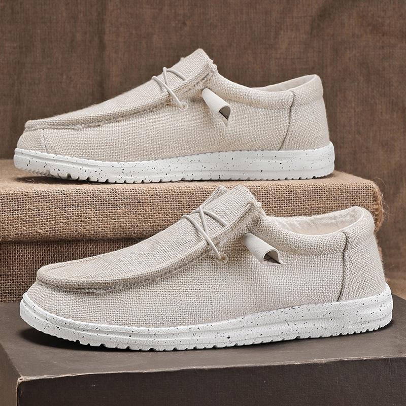 Beige Herren-Slipper aus Leinen mit weißer Sohle, lässiges Design, ideal für Sommermode. Bequeme Freizeitschuhe auf Leinenuntergrund.