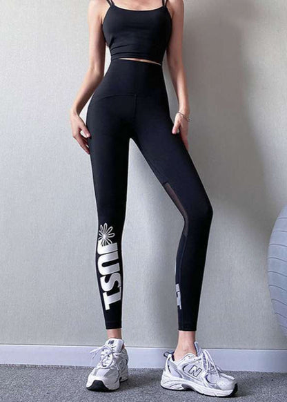 Frau in schwarzem Sport-BH und Leggings mit "USA"-Aufdruck, trägt weiße Turnschuhe. Fitnessmode, Sportbekleidung, athletischer Look.