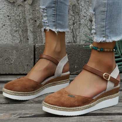 Damen Sandalen mit Keilabsatz, braunem Wildleder, verstellbarem Riemen und geflochtener Sohle, getragen mit zerrissenen Jeans. Sommermode, bequem.