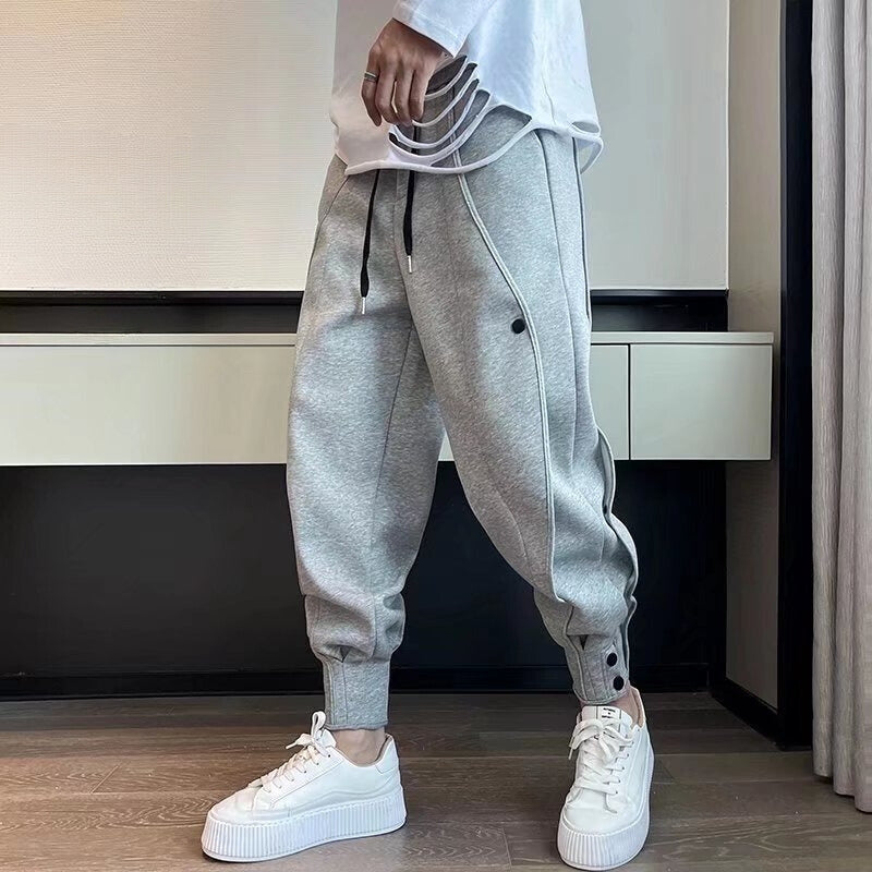 Person trägt graue Jogginghose mit schwarzen Kordeln und weißen Sneakers. Moderne Freizeitmode, bequeme Sportbekleidung, trendige Streetwear.