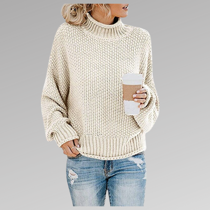 Frau in cremefarbenem Strickpullover mit Rollkragen hält Kaffeebecher, trägt zerrissene Jeans. Modetrend, Herbstmode, lässiger Look.