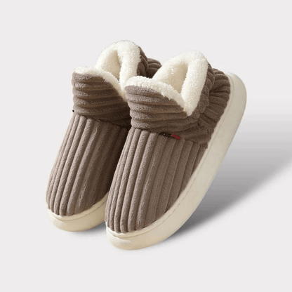 Braune, gestreifte Hausschuhe mit weißem Futter auf weißem Hintergrund. Bequeme, warme Pantoffeln für den Winter. Ideal für Zuhause.