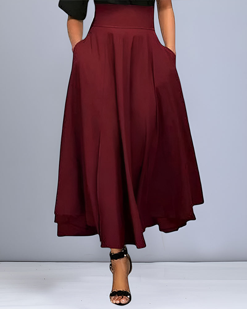 Frau trägt weinroten, knöchellangen A-Linien-Rock mit Taschen, kombiniert mit schwarzen Sandalen. Elegante Damenmode, stilvoller Look.