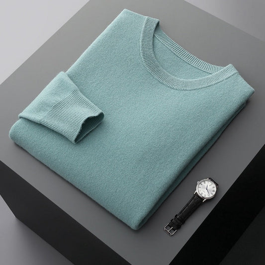 Gefalteter hellblauer Pullover aus Kaschmir auf grauem Tisch, daneben eine elegante Armbanduhr mit schwarzem Lederarmband und silbernem Zifferblatt.