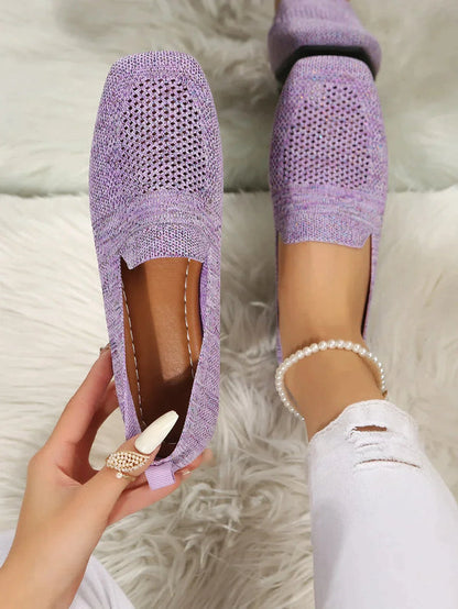 Lila gestrickte Damen-Loafer auf weißem Teppich, getragen mit zerrissenen weißen Jeans und Perlenknöchelband. Bequeme, stilvolle Freizeitschuhe.